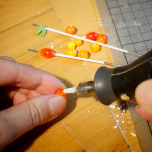 Glasperlen mit Dremel geschliffen, Glasperlen auf Metallstab, Hände